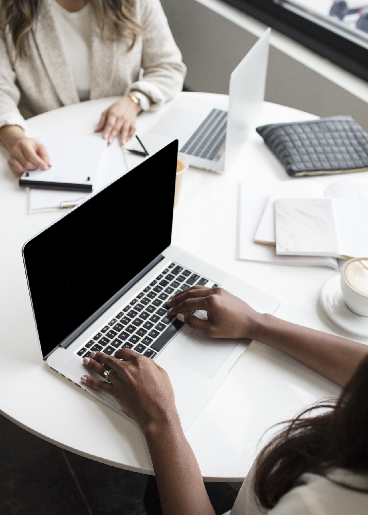 Overhead view of two people working across laptops and notebooks